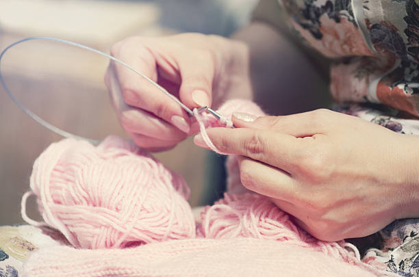 Girl doing crochet with yellow yarn and nails painted red, close up photography