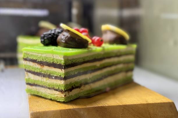 A portion of layered cream chocolate cake with blueberries and blackberries on a wooden stand