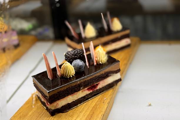 A portion of layered cream chocolate cake with blueberries and blackberries on a wooden stand