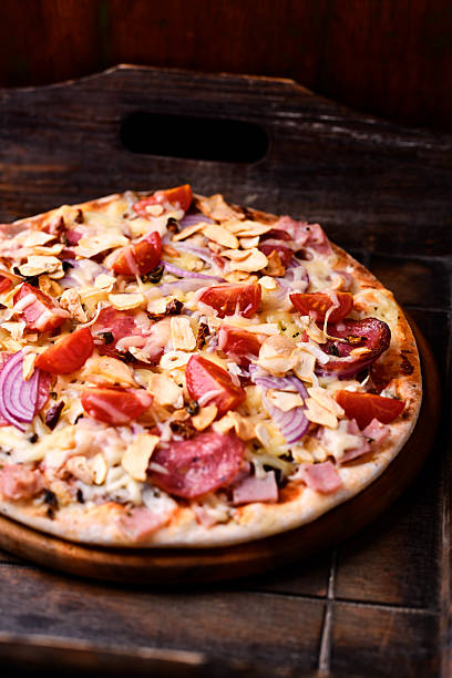 istock Pizza with ham, salami, cherry tomatoes and mozzarella cheese. Rustic wooden background. Soft focus. Close up. 2235164640