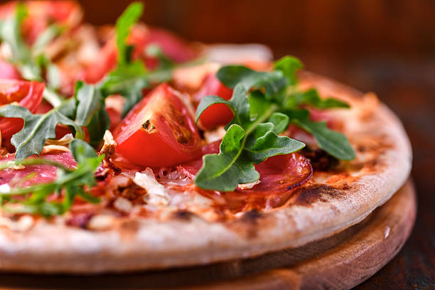 istock Pizza with ham, salami, tomatoes and mozzarella cheese. Rustic wooden background. Soft focus. Close up. 2235164783