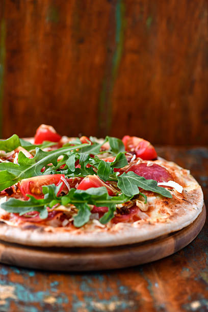 istock Pizza with ham, salami, tomatoes and mozzarella cheese. Rustic wooden background. Soft focus. Close up. 2235165810