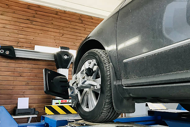 istock Comprehensive Vehicle Tire Alignment Service Offered in a State-of-the-art Workshop. A vehicle is currently undergoing a comprehensive tire alignment process in a highly professional garage setting 2235167534