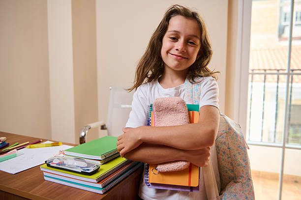 istock Smiling Schoolgirl Holding Notebooks in Study Environment With Natural Light 2235172504