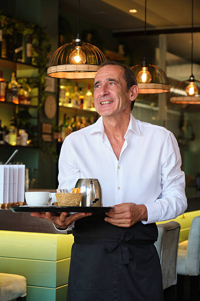 istock Smiling waiter carrying a tray with coffee and tea in a restaurant 2235175963