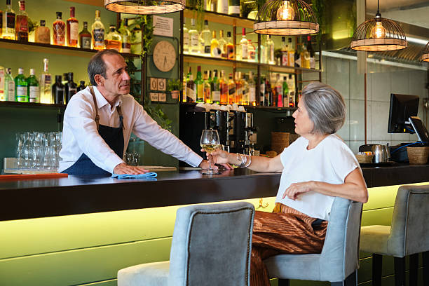 istock Bartender serving wine to a mature woman at the counter 2235177546