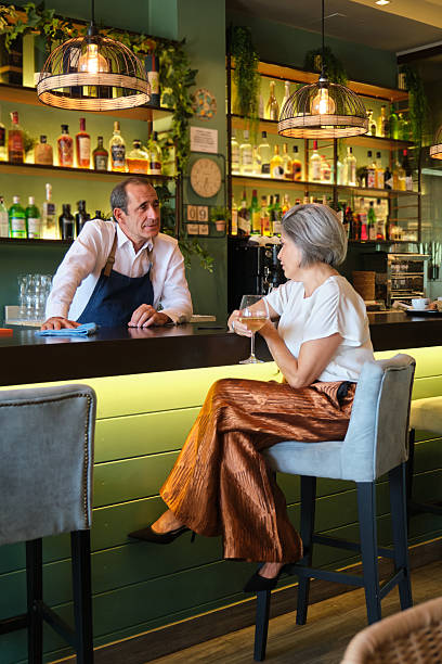 istock Bartender talking with elegant mature woman sitting at bar counter 2235177707