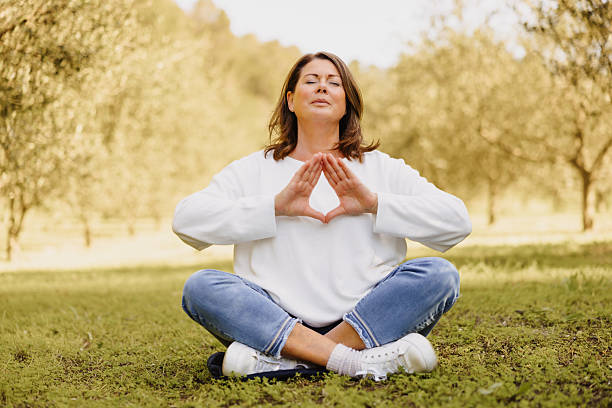 istock Mature woman meditating cross legged among olive trees in mindfulness pose 2235182046