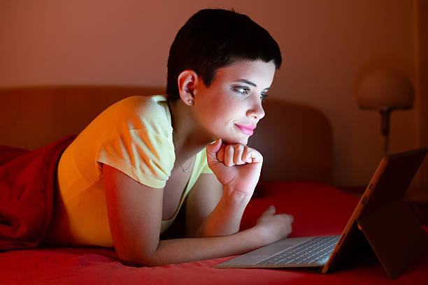 istock Young woman lying in bed and using laptop 2235186119