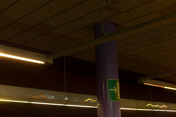 There stands a striking purple pole featuring a prominently displayed green arrow pointing in a specific direction on it