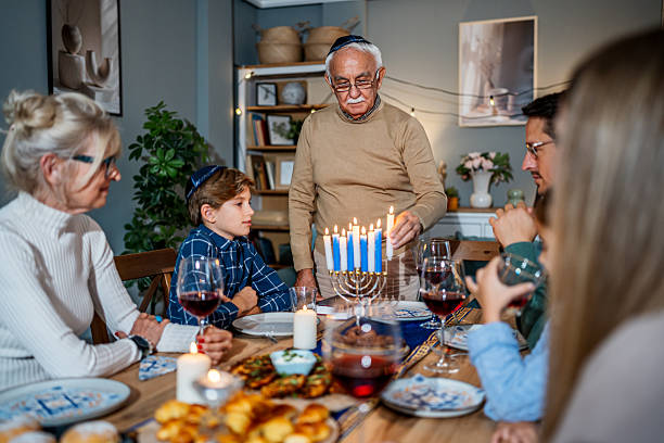 istock Family celebrating Hanukkah lighting menorah candles during dinner 2235195802