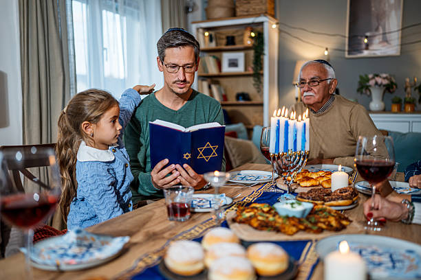 istock Family celebrating Hanukkah reading from the torah at dinner table 2235195920