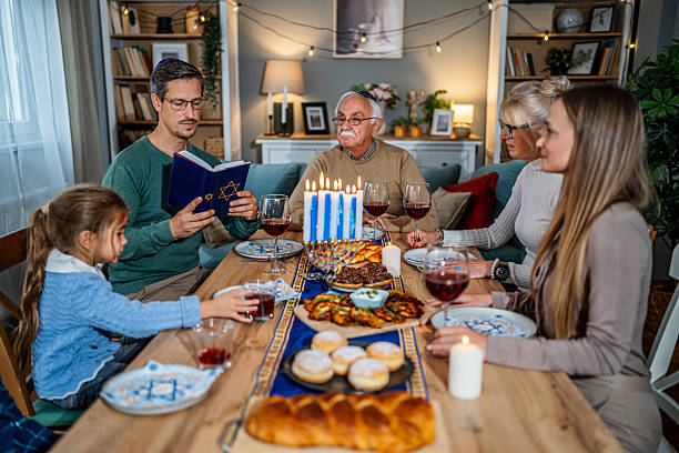 istock Family celebrating Hanukkah reading from the torah at dinner table 2235195968