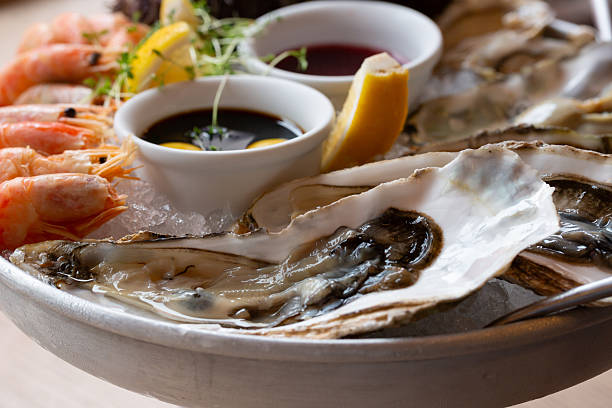 istock Seafood (oysters, shrimps, sea-urchins, mussels) are decoratively put on ice in a big plate 2235197208