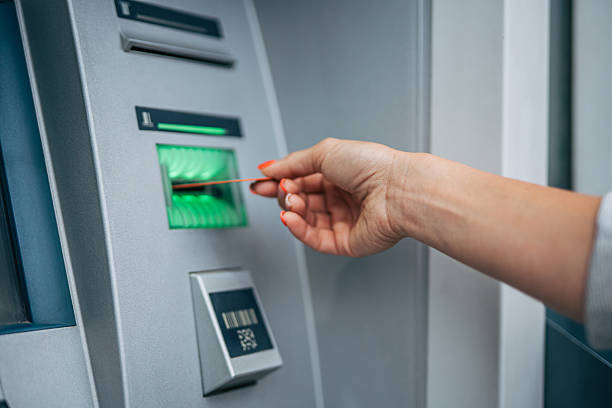 istock Woman inserting credit card into atm for banking transaction 2235197443