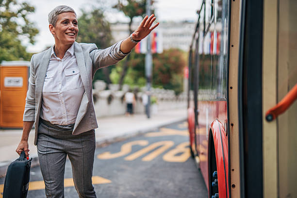 istock Businesswoman waving to bus driver while holding briefcase 2235197497