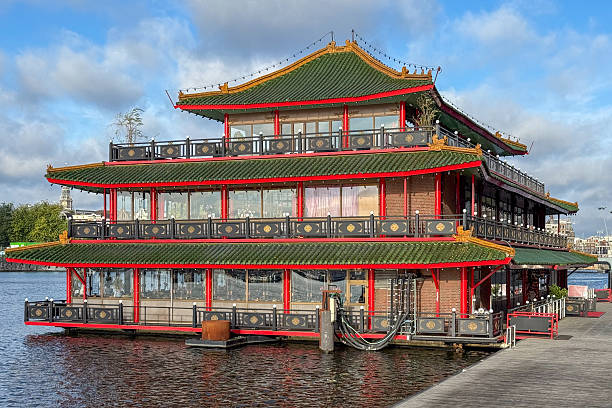 Amsterdam, The Netherlands. September 13th, 2025: The Chinese restaurant Sea Palace, a floating dining pavilion, gleams on the water’s edge near Prins Hendrikkade. Traditional Chinese lanterns and ornate roof details stand out against Amsterdam’s historic canal houses and moored boats. The scene captures both the architectural elegance of Sea Palace and the unique waterfront ambiance of the city.