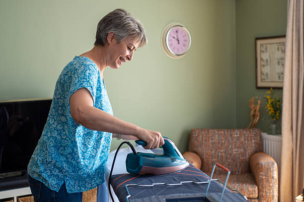 Beautiful mature woman with gray hair ironing at home