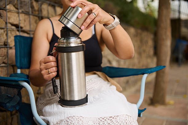 Woman Using Thermos Outdoors While Sitting on Chair Relaxing