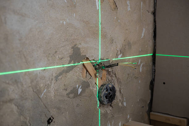 istock Green laser level projects straight horizontal and vertical lines onto concrete wall during home renovation, providing accurate measurements for electrical work. Laser level alignment. 2235220813