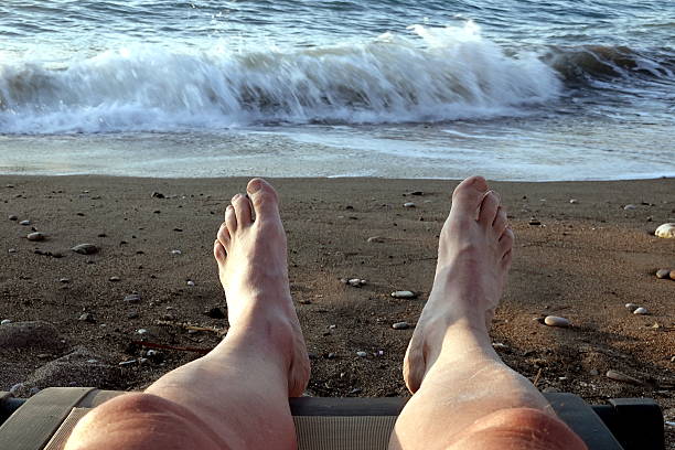 istock Man's feet on the seashore. 2235225022