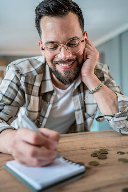 istock Young man writing notes and calculating home budget 2235228648