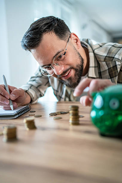 istock Young man saving money and taking notes of his home budget 2235228709