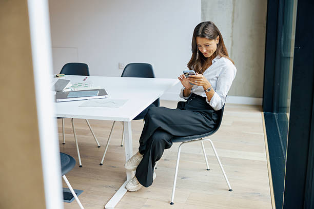 istock A young woman fully engaged with her smartphone while seated in a modern workspace environment 2235233861