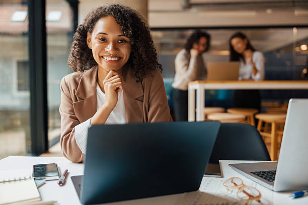 istock A Professional Woman Smiling in a Contemporary Office Environment Surrounded by Laptops 2235234657
