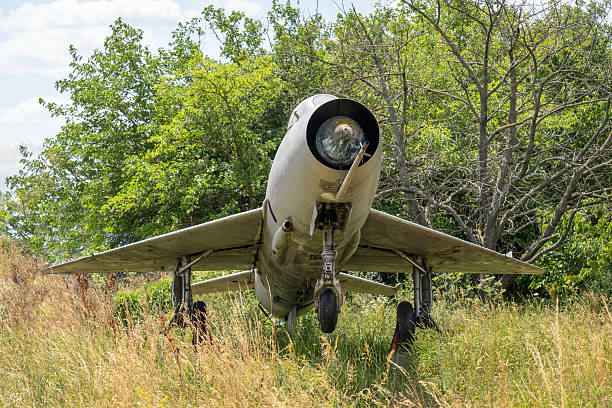 Old Soviet-made metallic Mig-21 fighter jet in an abandoned green field