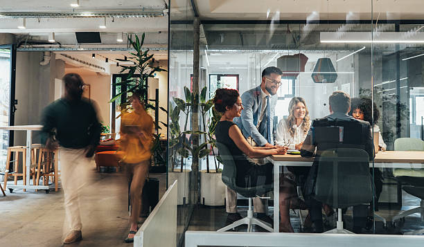 A diverse team of professionals engaged in a collaborative business meeting inside a modern glass-walled conference room