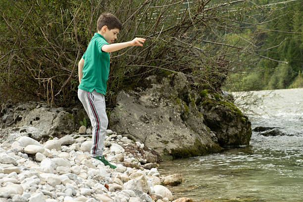 istock Boy throwing stones into the river, child communication with nature 2235247108
