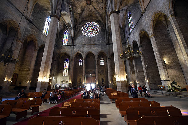 Santa Maria del Mar is a gothic church in the Ribera district of Barcelona, built between 1329 and 1383. The image shows the main nave of the wonderful church with some people on benches.