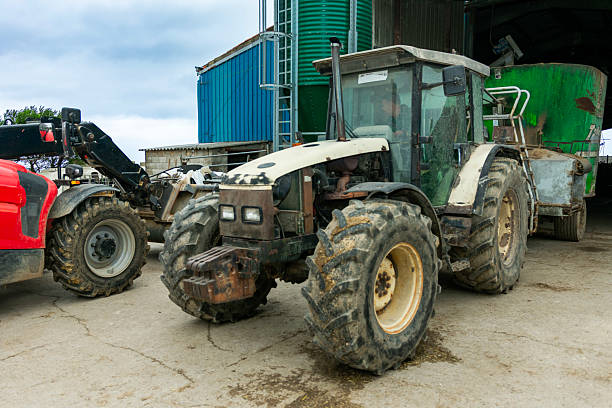 istock Farmer driving tractor with trailer in farmyard 2235251618