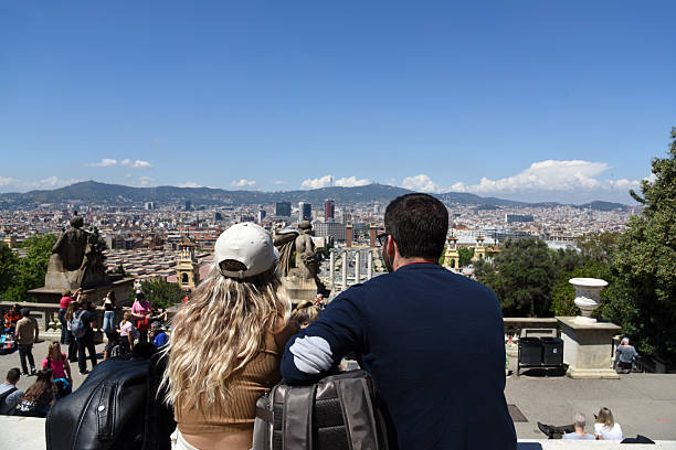 A couple seen from behind looking to the wonderful City of Barcelona. Captured on a sunny day during spring season.