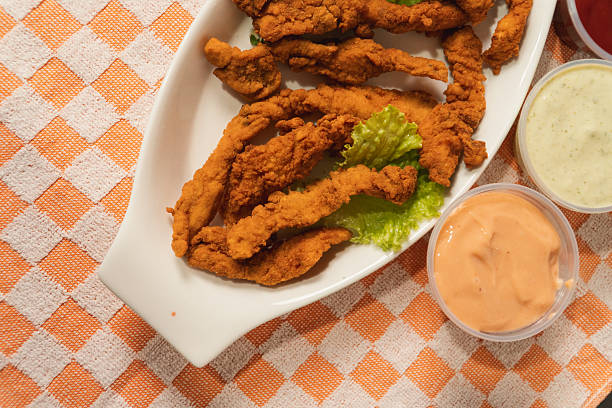 istock Close-up view of fried chicken strips with sauces on a checkered tablecloth. 2235255270