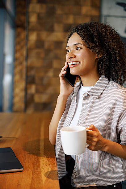 istock A Woman Relishing Her Coffee While Engaging in a Phone Conversation in a Cozy Cafe 2235255934