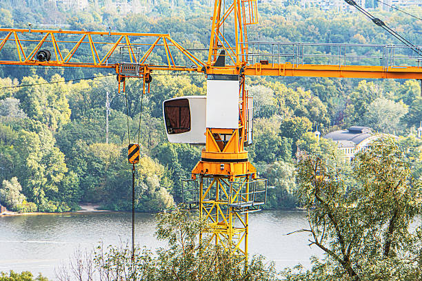 istock A bustling construction site with a tall, yellow tower crane amidst lush greenery, near a body of water and under natural lighting a 2235264829