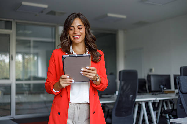 istock Young businesswoman smiling while holding a digital tablet in a modern office, embodying professionalism and leadership in her career 2235270904