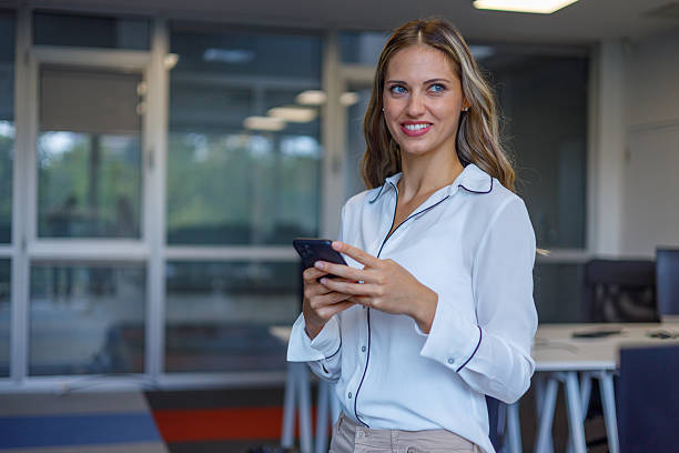 istock Young businesswoman smiling while using a smartphone in a modern office, exuding confidence and positivity in her professional environment 2235271146