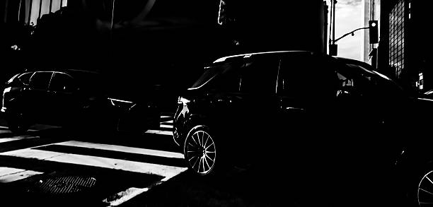 MONOCHROME SENSOR SERIE : This image, captured with a monochrome sensor camera, depicts a nighttime urban scene featuring two cars near a crosswalk. The striking contrasts between deep shadows and bright highlights create a dramatic, cinematic atmosphere. \n# The rich grayscale values add a sophisticated texture, making it an excellent backdrop for an artistic creation. # It could be used by a creator for various occasions:  Abstract art project: as a background for overlaying graphic elements or illustrations.  \n# Fashion photography: for a dark, elegant shoot.  \n# Movie or series poster: its mysterious aesthetic suits a thriller or drama.  # Music album design: ideal for genres like jazz or electro-dark. # Free of AI