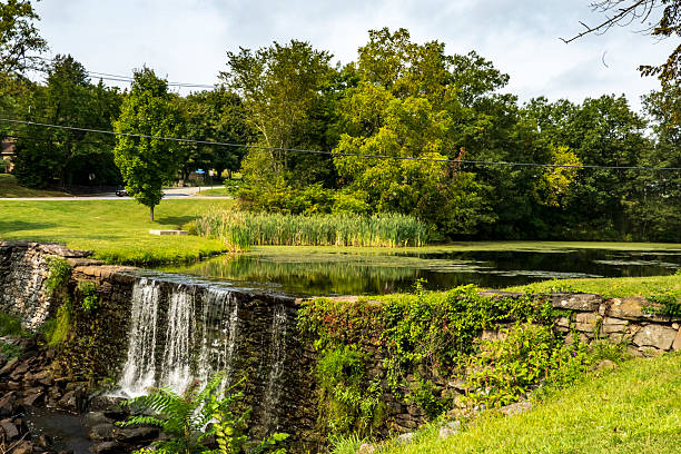 Monroe, NY - US - Sep 6, 2025: Picturesque Smith's Mill dam and pond in Monroe, New York, featuring a flowing waterfall, tranquil water, and vibrant green landscape under a serene sky