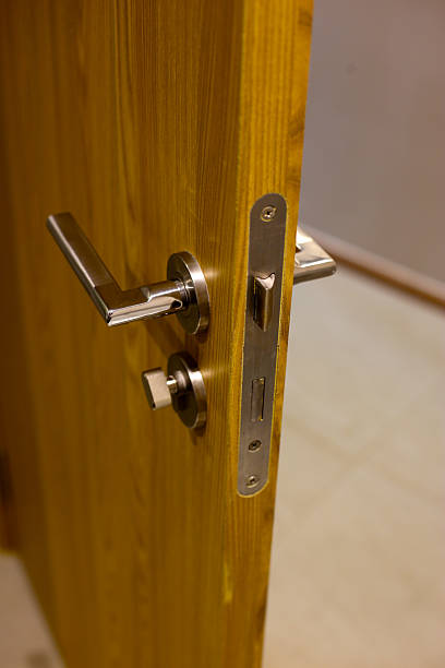 istock Wooden door with modern stainless steel handle and lock, slightly open 2235288604