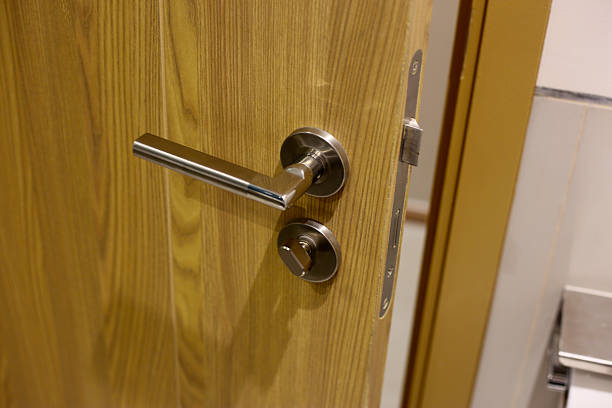 istock Wooden door with modern stainless steel handle and lock, slightly open 2235289183