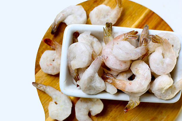 istock Frozen shrimps in a white bowl on wooden board. 2235289914