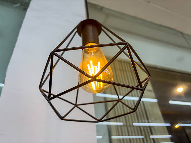 istock Geometric cage pendant light with Edison bulb creating warm ambiance, showcasing modern design against blurred background offering minimalist aesthetic and architectural accent lighting solution 2235290912