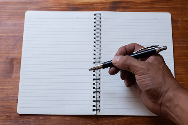 istock A person holding a ballpoint pen and a blank notebook 2235292800