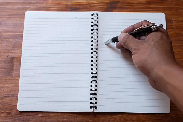 istock A person holding a ballpoint pen and a blank notebook 2235292811