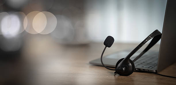 istock Customer support concept with headset and laptop on wooden desk, symbolizing online communication, helpline assistance, call us service, and professional contact center. 2235295157