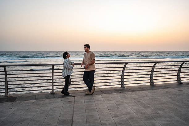 istock Diverse Pair Conversing by the Corniche Promenade at Sunset 2235298047
